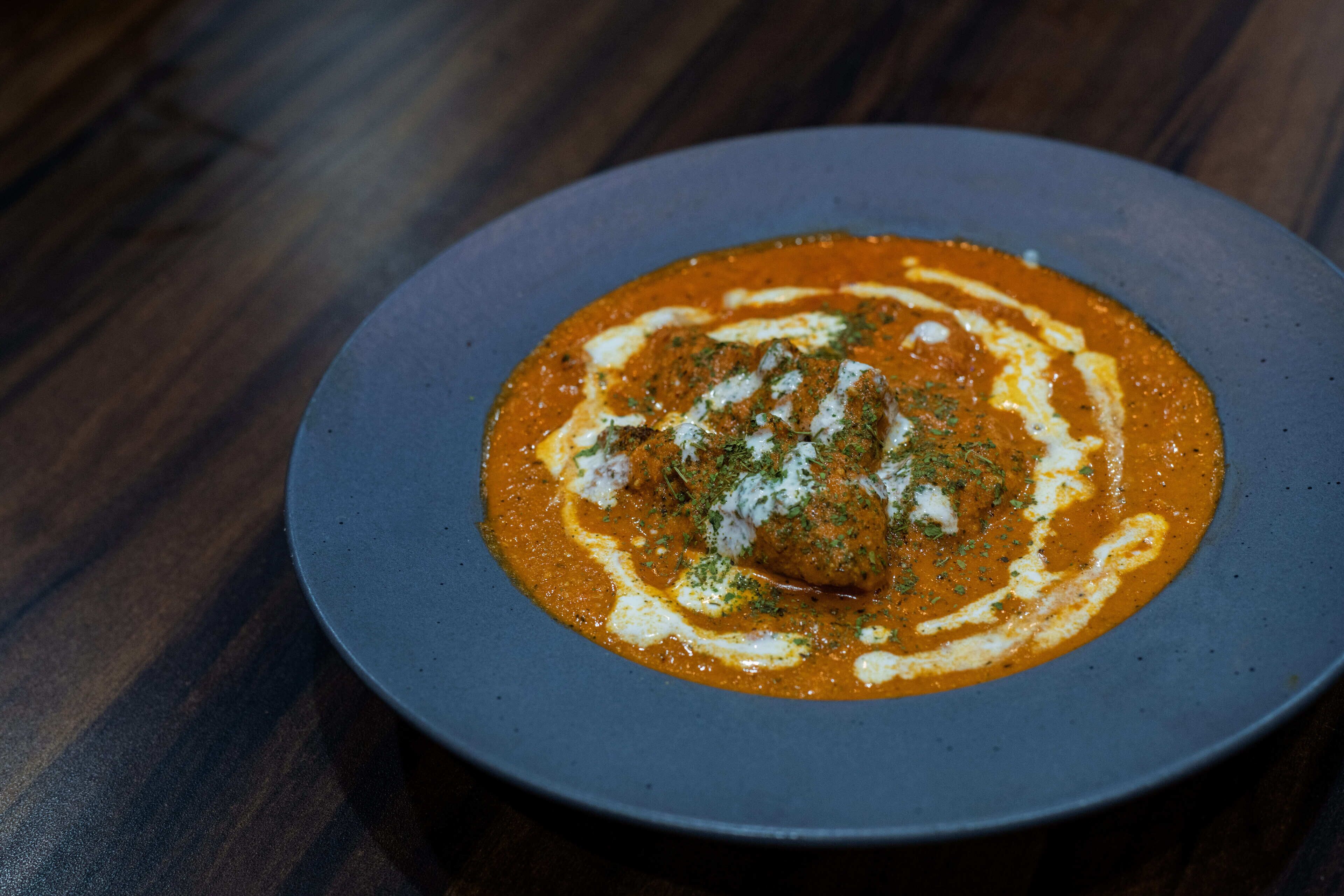 A plate of food with a creamy sauce and a dollop of cream on top, placed on a dark surface.
