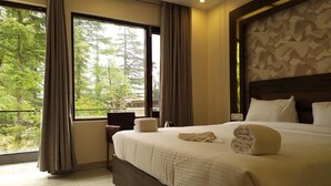 A hotel room with a large bed, a view of trees through the window, and a modern design. - Golden Rock - AM Hotel Kollection (Dharamshala)