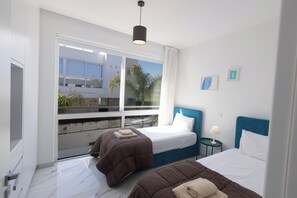 Une chambre d’hôtel moderne avec deux lits, une grande fenêtre et une vue sur l’extérieur.