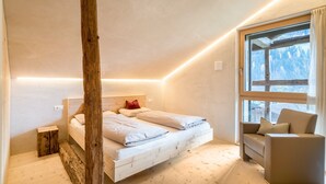 A bedroom with a bed, a window, a wooden post, and a sofa. - Chalet 'Ferienhaus Im Stadl' with Mountain Views, Private Terrace and Wi-Fi (St. Martin in Passeier)