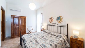 Un dormitorio con cama, armario de madera y dos cuadros de peces.