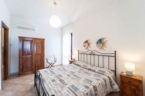 Une chambre à coucher avec un lit, une armoire en bois et deux œuvres d’art murales représentant des poissons.