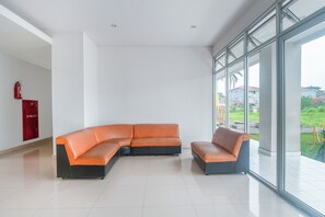 A modern interior with a sectional sofa, a fire extinguisher, and large windows. - Life 2837 Apartment Dramaga Tower (Dramaga)