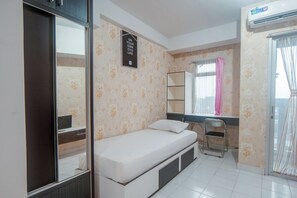 Une pièce comprenant un lit, une chaise, un bureau, une armoire et une fenêtre avec des rideaux.