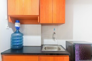 Une cuisine avec des meubles de rangement en bois, un évier et un distributeur d’eau.