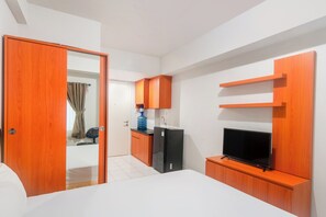A compact hotel room with a bed, a TV, a small kitchenette, and a wardrobe. - Life 2837 Apartment Dramaga Tower (Dramaga)