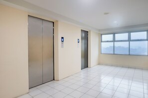 A hotel room with a large window, a door, and a tiled floor. - Life 2837 Apartment Dramaga Tower (Dramaga)
