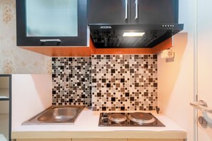 A kitchen with a black range hood, a tiled backsplash, and a stainless steel sink. - Life 2837 Apartment Dramaga Tower (Dramaga)