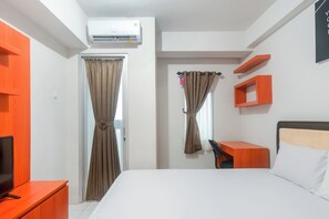A hotel room with a bed, a desk, a TV, an air conditioner, and curtains. - Life 2837 Apartment Dramaga Tower (Dramaga)