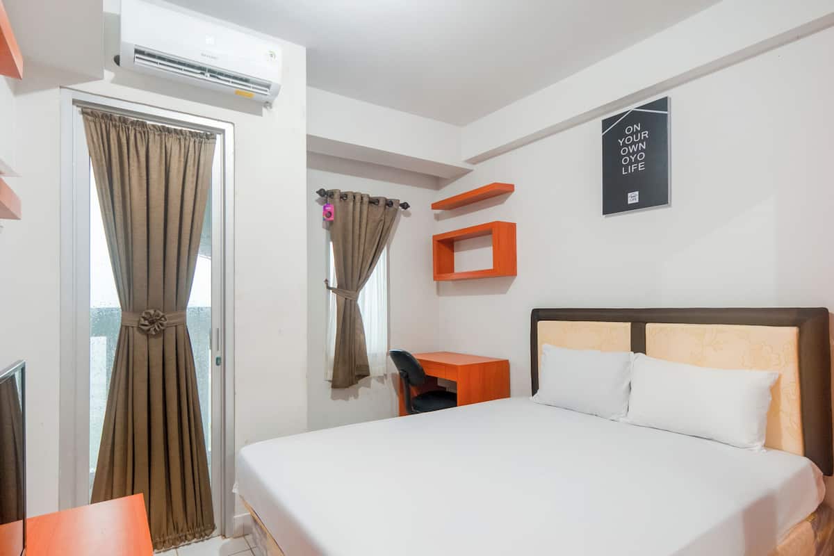 Une chambre d’hôtel équipée d’un lit, d’un bureau, d’une chaise, d’un climatiseur et d’une fenêtre avec des rideaux.