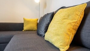 Moderni olohuone, jossa on harmaa sohva ja kaksi koristetyynyä, toinen keltainen ja toinen harmaa.