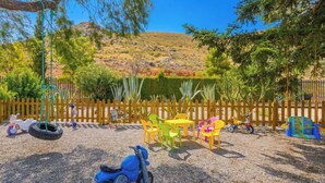 A playground with a tire swing, a scooter, and colorful plastic chairs and tables. - La Guitarra Andaluza Loja by Ruralidays (Granada)