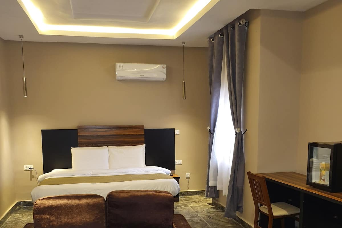 A hotel room with a bed, a sofa, a desk, and a TV.