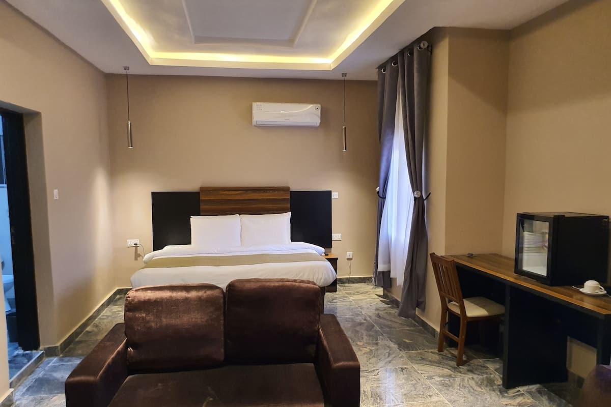 A hotel room with a bed, a TV, a desk, and a sofa.
