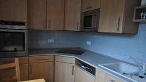 A kitchen with wooden cabinets, a built-in microwave, a dishwasher, and a stainless steel sink.