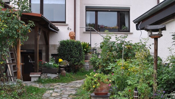 A two-story house with a stone pathway leading to the entrance.