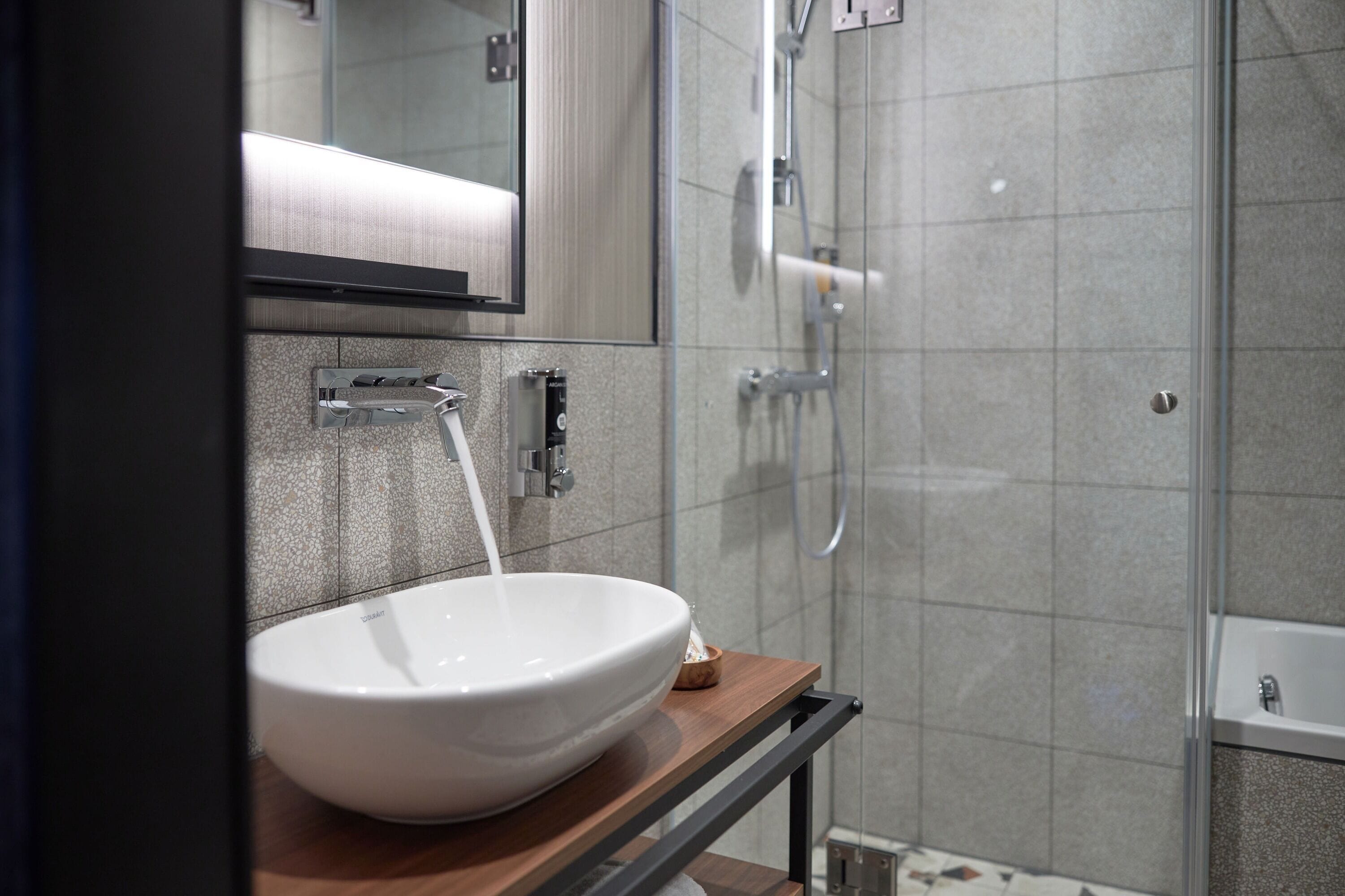 Ein modernes Badezimmer mit einem weißen Waschbecken, einem Spiegel und einer Duschkabine.