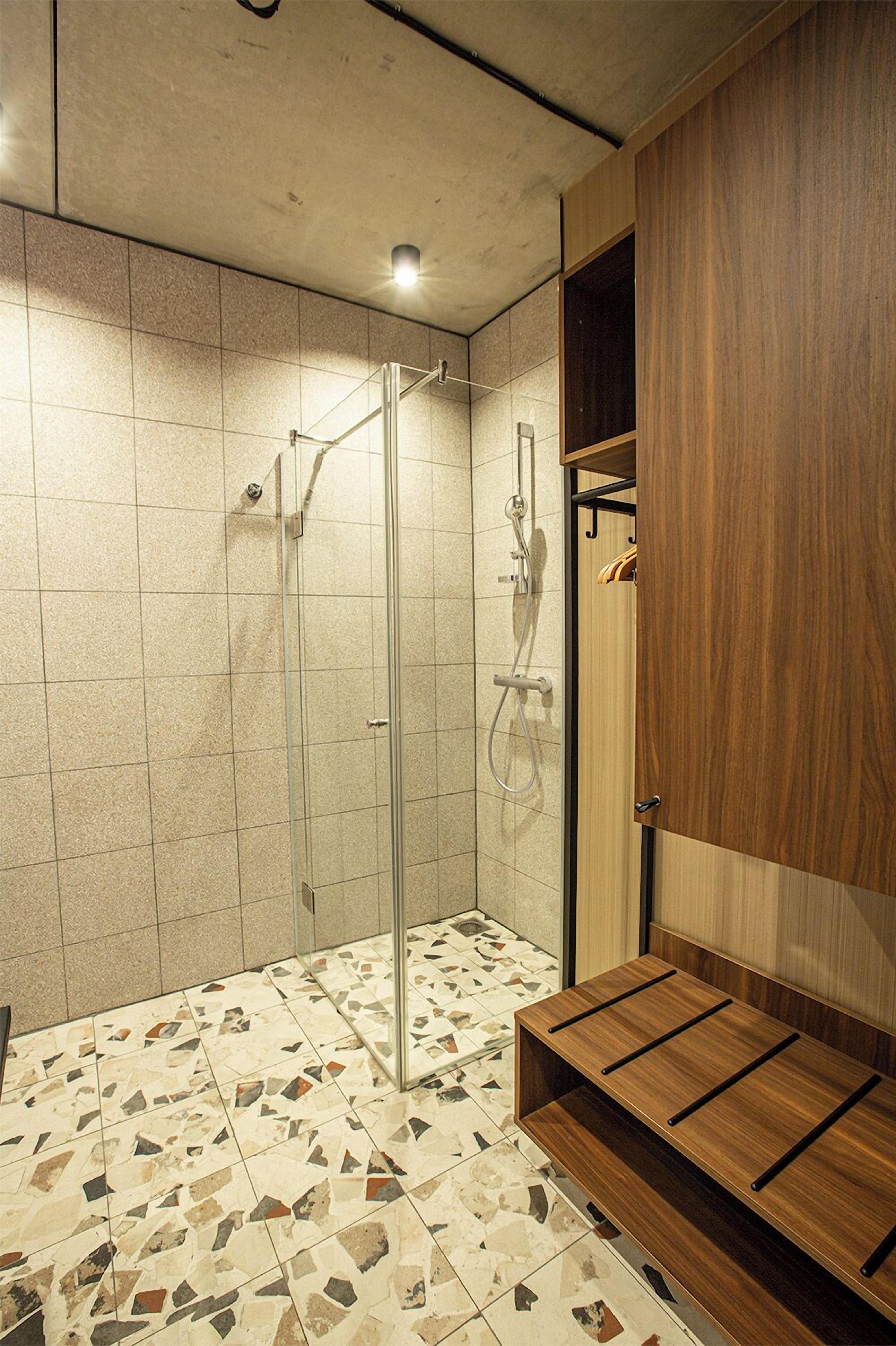 Een moderne badkamer met een douchecabine van glas, een houten wastafelmeubel en een vloer van mozaïektegels.