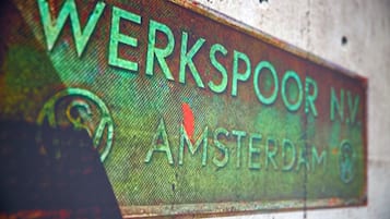 Un letrero con el texto 'WERKSPOOR NV AMSTERDAM' sobre un fondo texturizado.