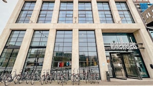Un hôtel moderne, avec une façade en verre, de nombreux étages et une entrée bien visible où figure le nom de l’hôtel.