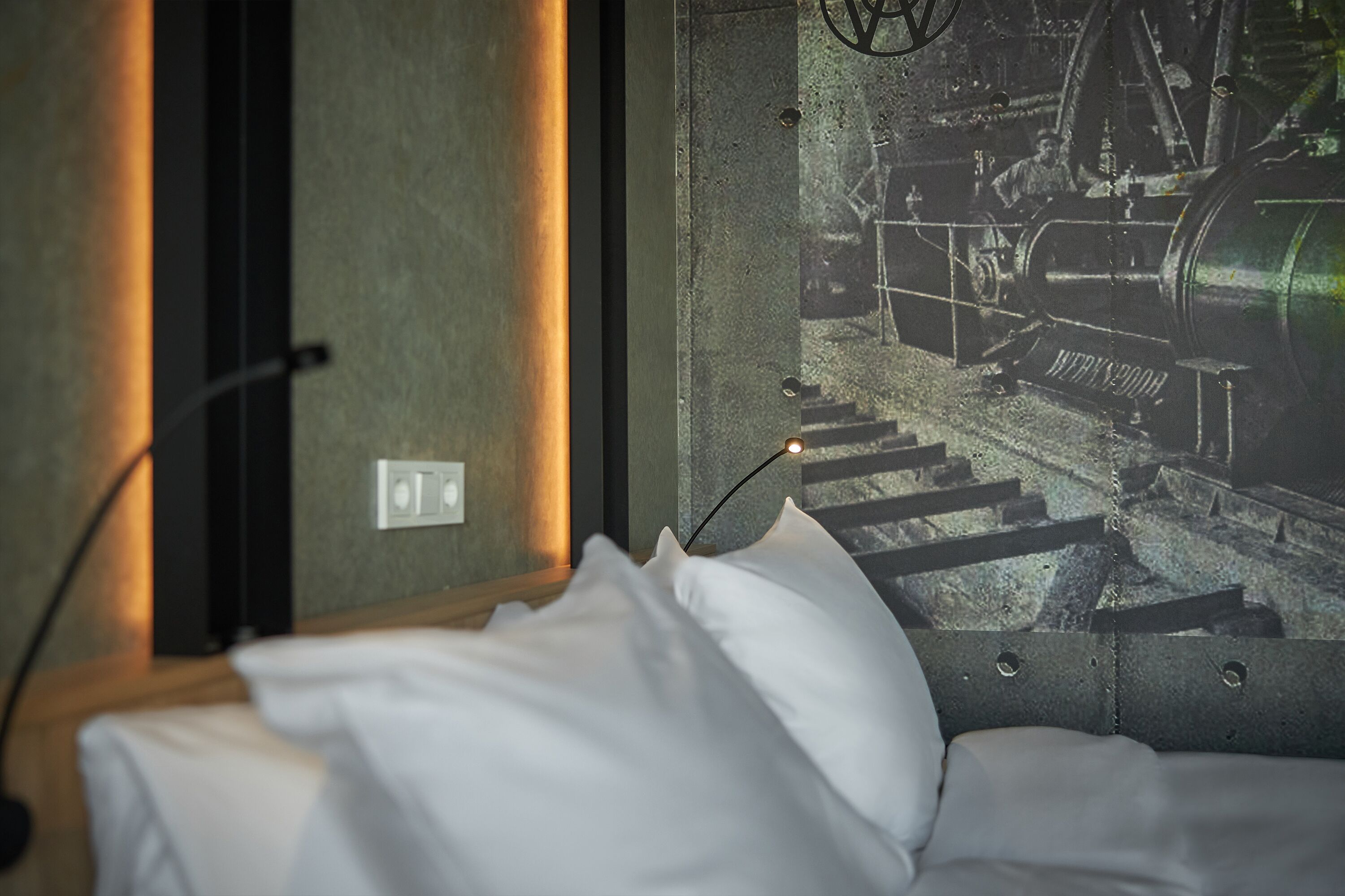 Una cama con sábanas blancas y vista a un tren por la ventana.