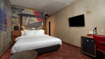 Une chambre d’hôtel avec un grand lit, un bureau, une chaise, une télévision et une fresque murale.