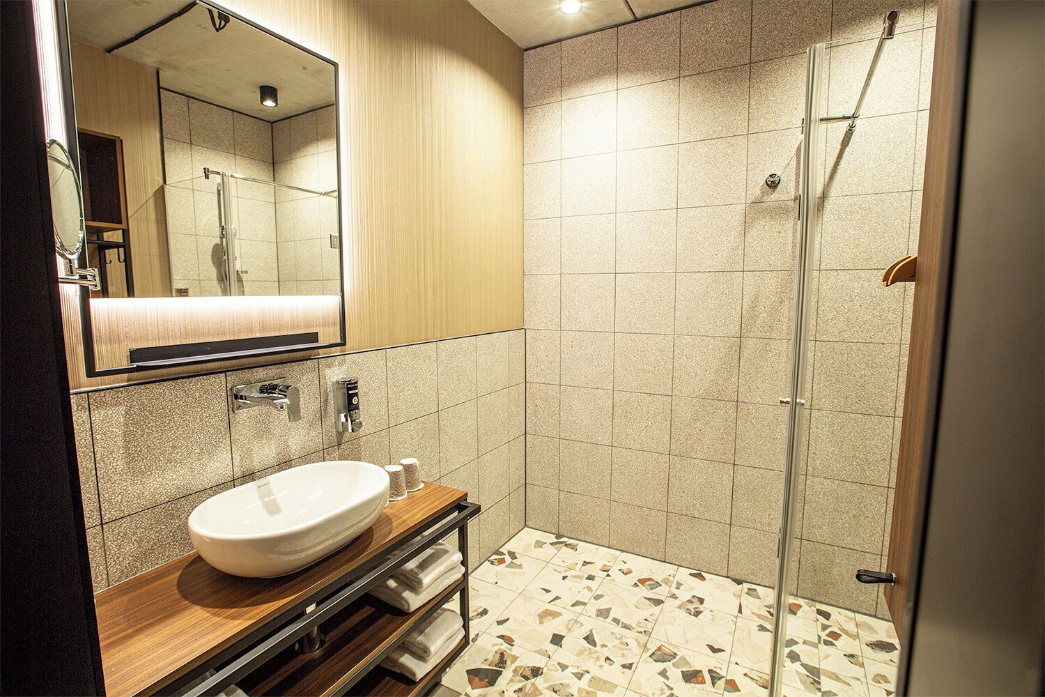 Une salle de bain moderne avec un grand miroir, un lavabo et une douche.