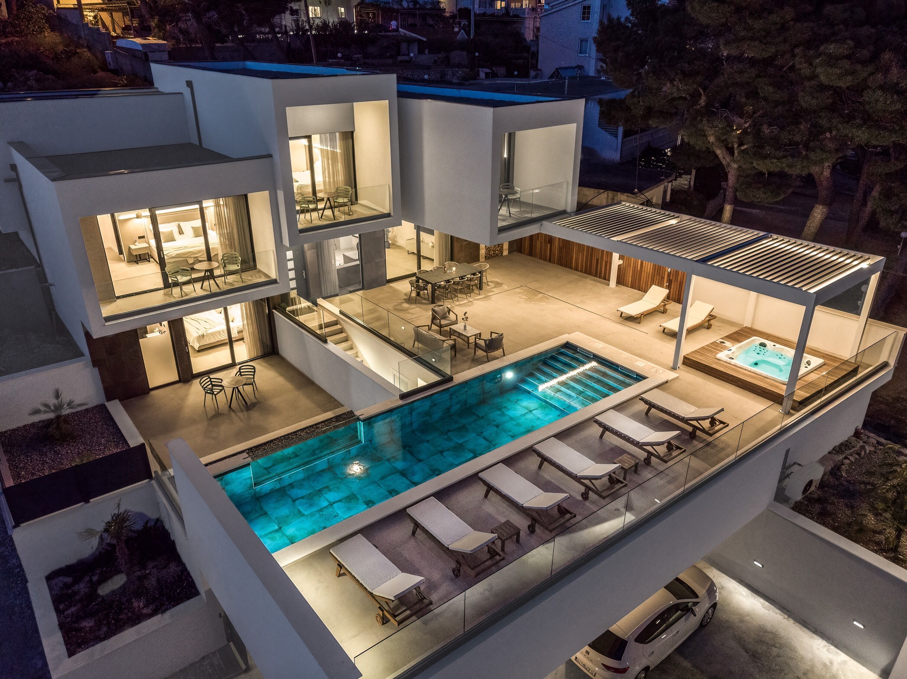 Una casa moderna de varios pisos con piscina en la azotea, mobiliario exterior y un interior bien iluminado.