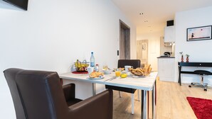 A modern dining area with a table set for breakfast, including croissants, fruit, and beverages. - Prim Loge (Balgheim)