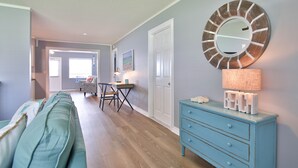 Un salon avec un canapé bleu, une commode bleue dotée d’un miroir et un plancher en bois.