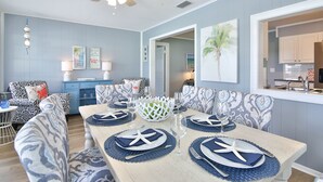 Un coin repas avec une table dressée pour six personnes, agrémenté de serviettes décorées d’étoiles de mer et d’un bol décoratif.