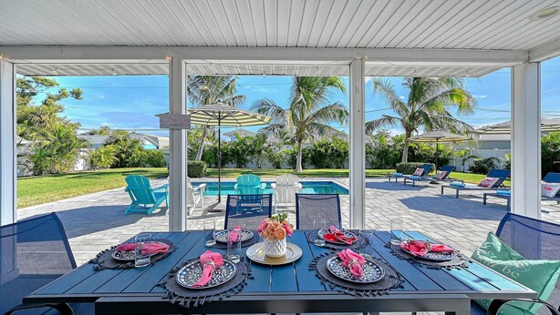 Une terrasse extérieure avec une piscine, des chaises longues et une table à manger pour six personnes.