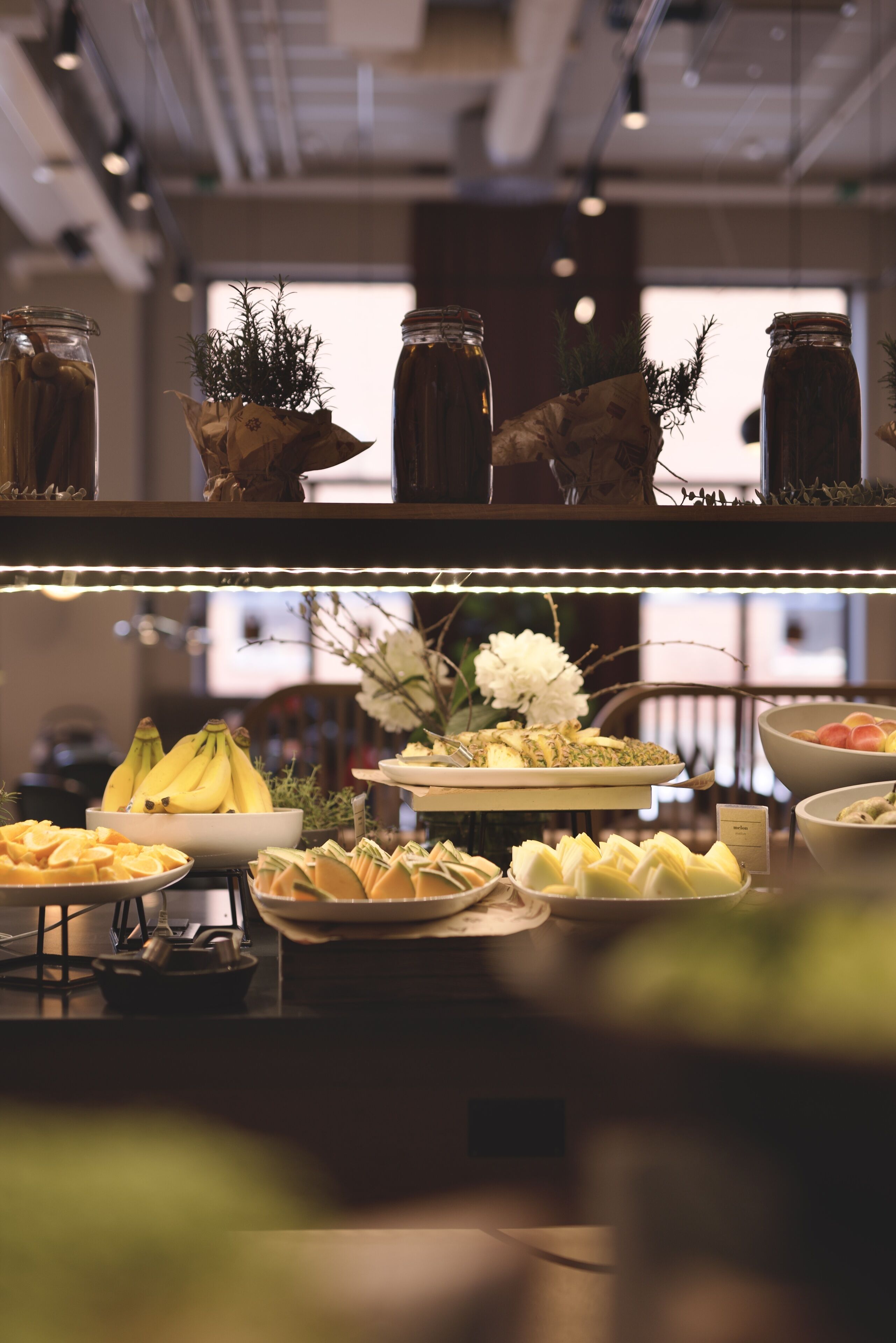 A buffet with various food items including bananas, pastries, and a floral arrangement.