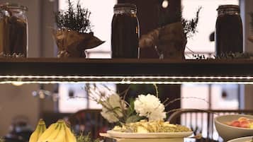 A buffet with various food items including bananas, pastries, and a floral arrangement.