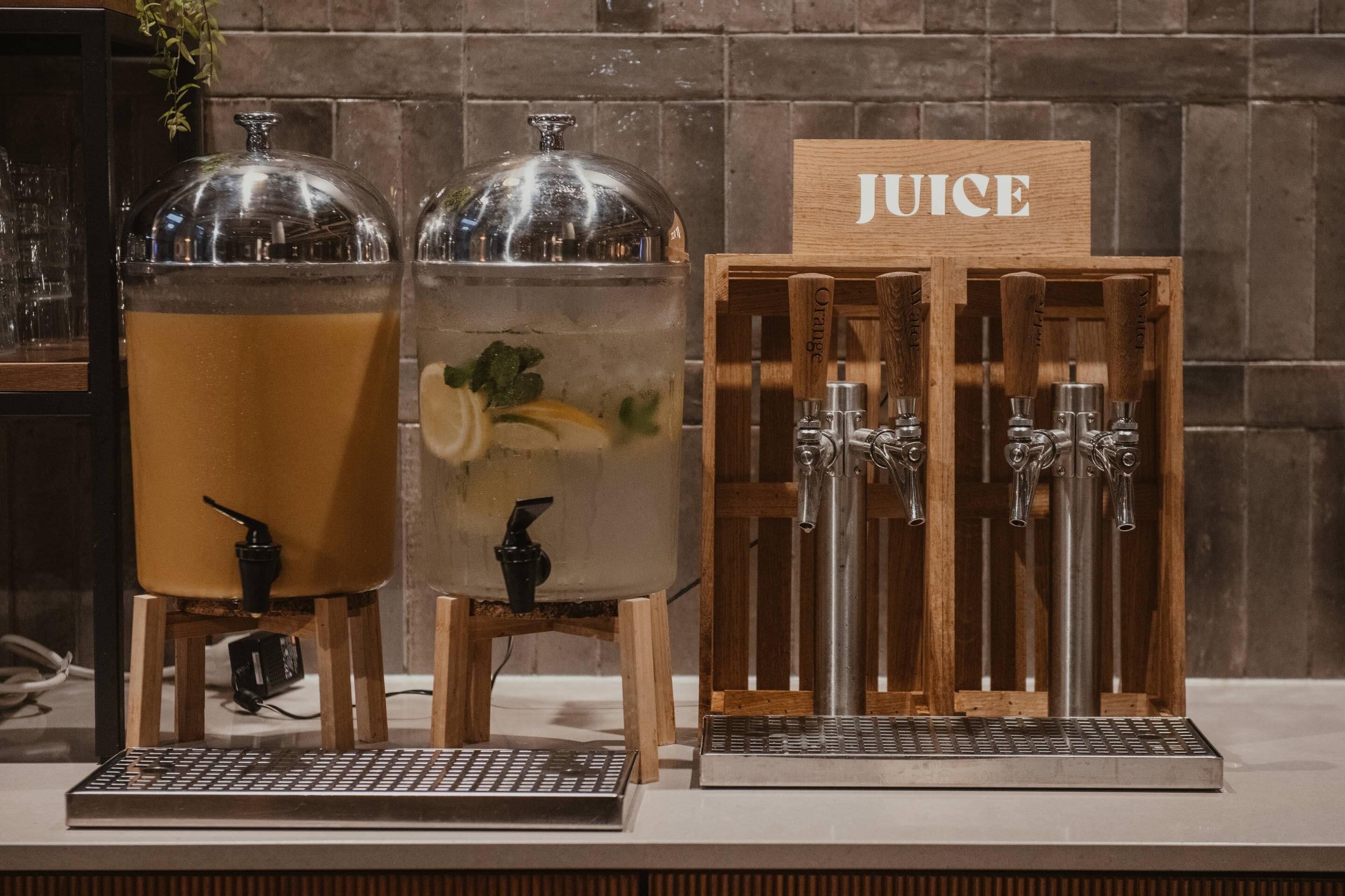 Dos dispensadores de bebidas, uno con la etiqueta 'JUICE' y otro con un diseño de frutas, ambos sobre una encimera.