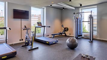 Ein modernes Fitnessstudio mit Laufbändern, Crosstrainern, einem Rudergerät, einer Medizinball und einem Squat-Rack.
