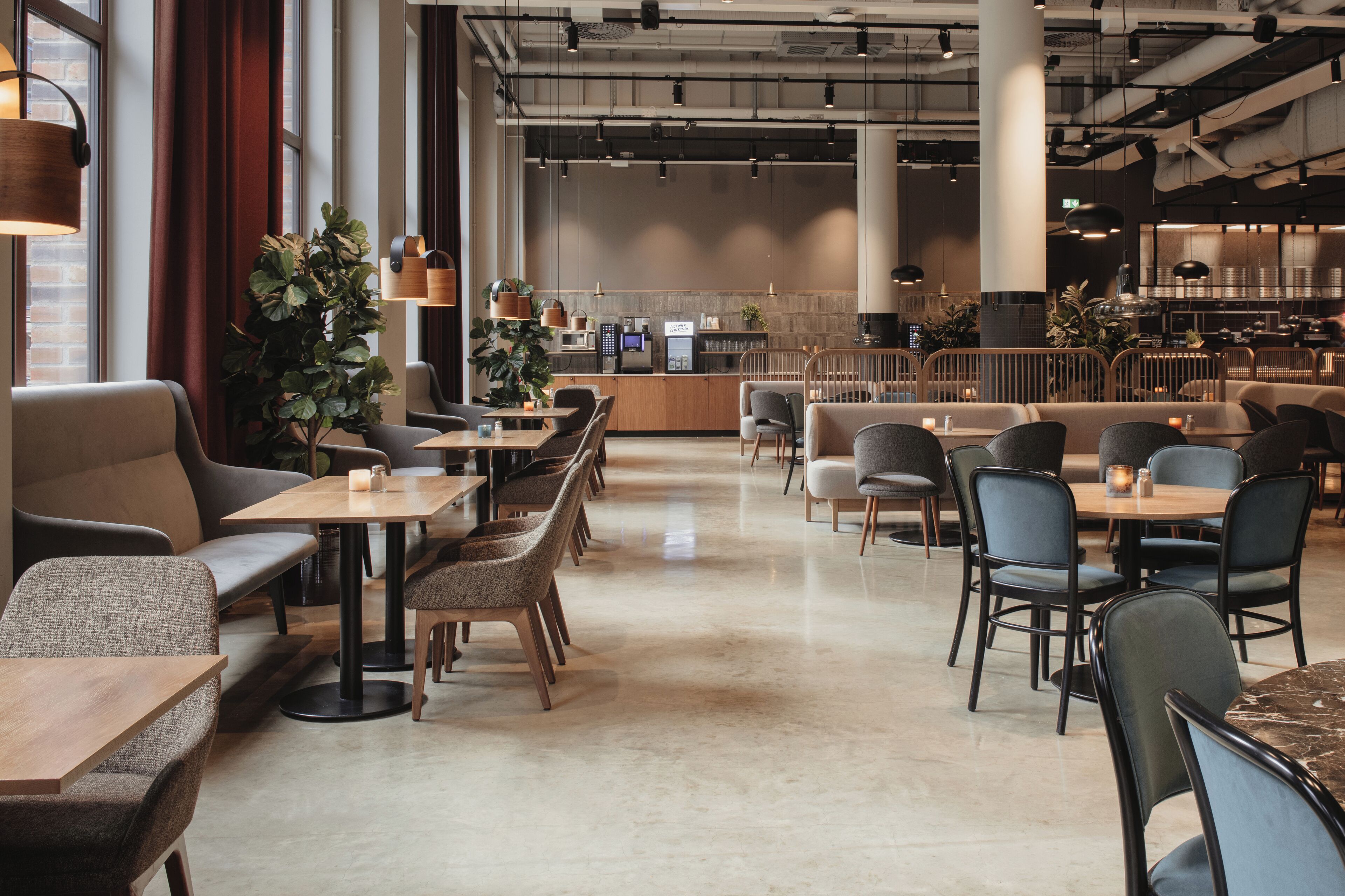Un café moderno con arreglos de asientos, una barra y una cocina a la vista.