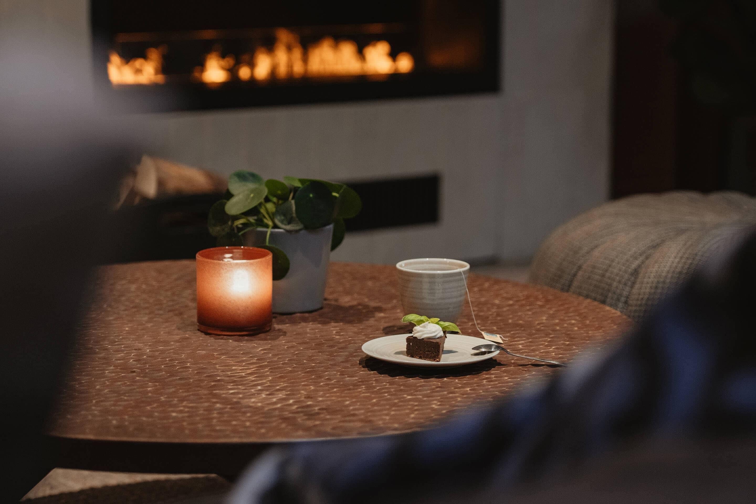 A table with a candle, a small plant, and a plate with a dessert.