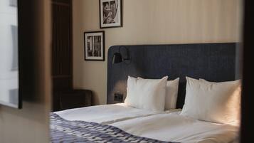 A hotel room with a bed, a headboard, a nightstand, and two framed pictures on the wall.