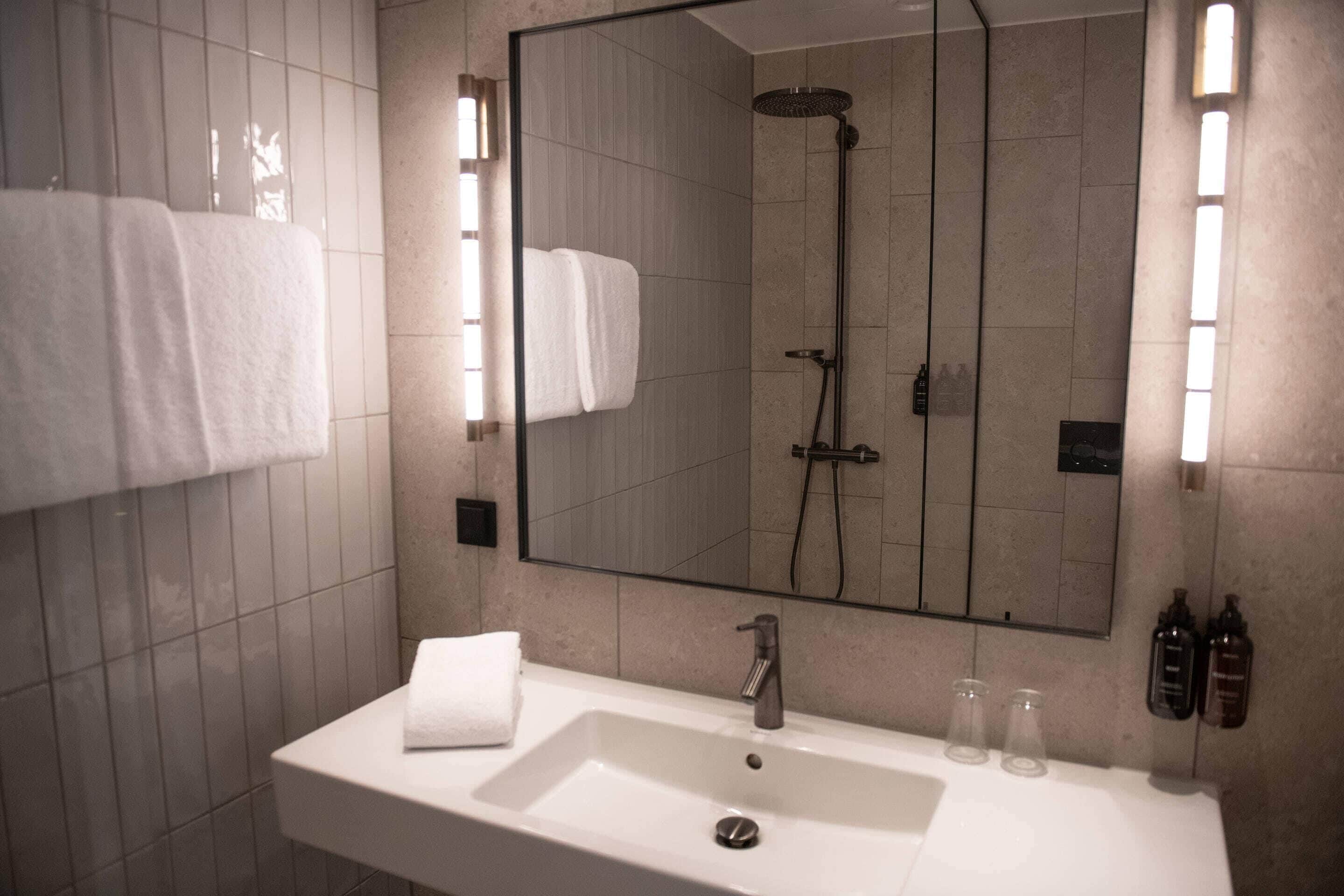 A bathroom with a sink, mirror, and shower.