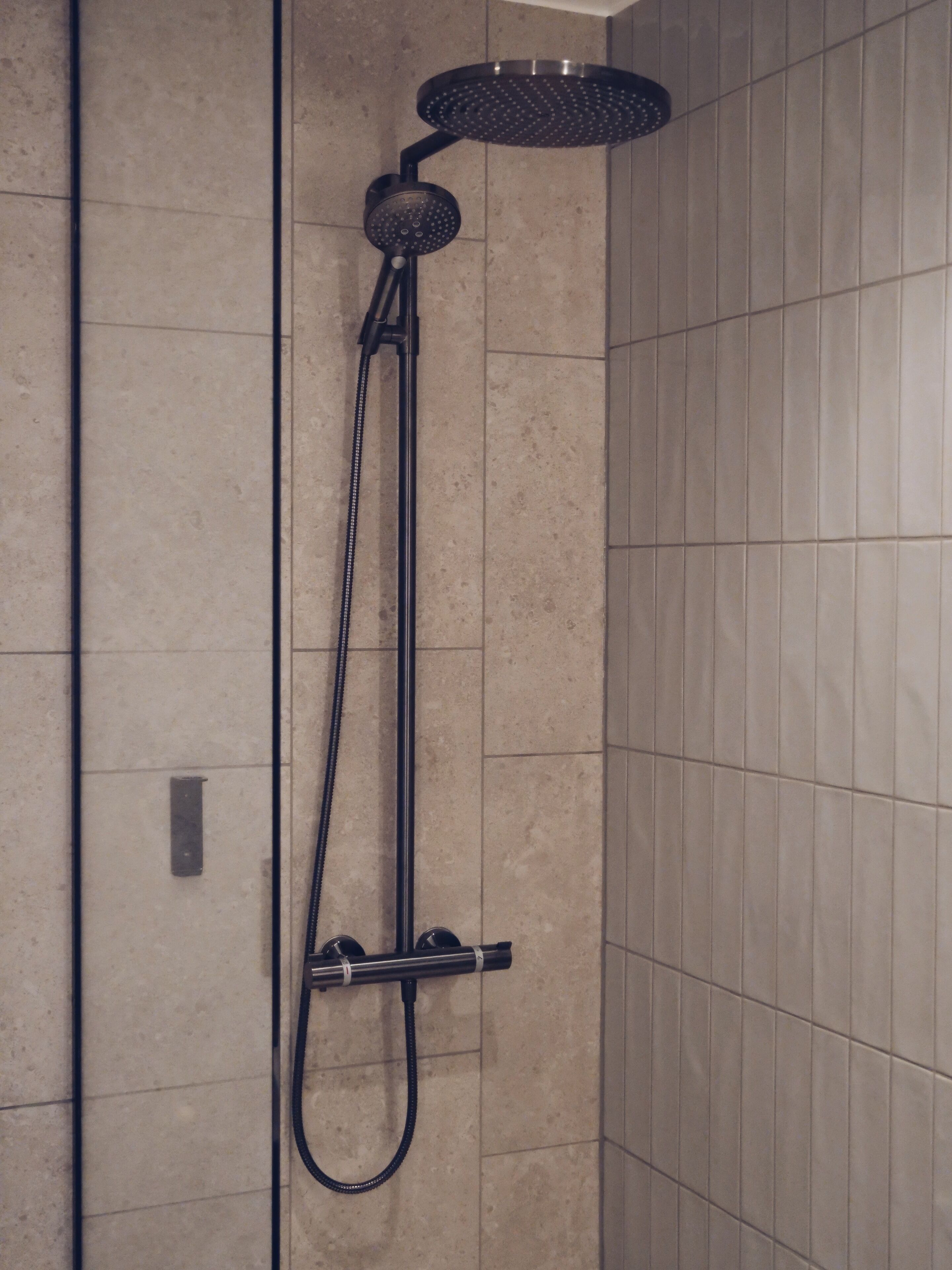A shower with a handheld showerhead and a fixed showerhead mounted on the wall.