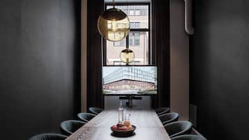 A modern conference room with a long table, chairs, and a large window with a view of a building.