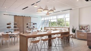 A modern kitchen with a central island, bar stools, and a Chobani refrigerator. - Element by Marriott Orlando at SeaWorld (Orlando)