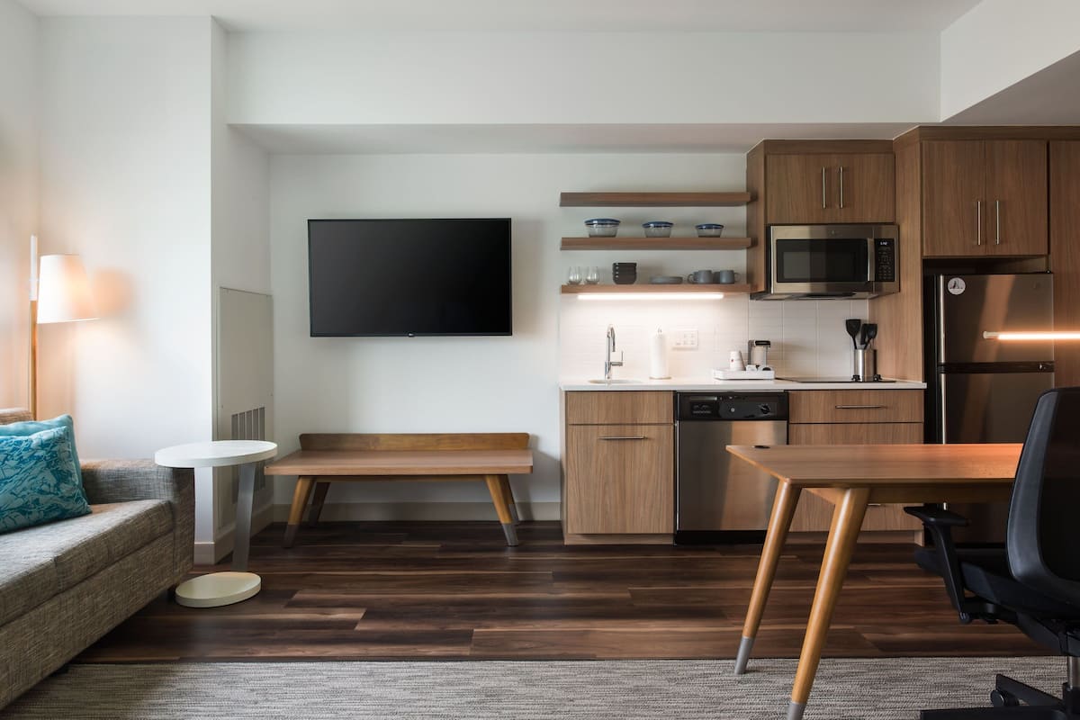 Een moderne keuken met houten kastjes, een ingebouwde magnetron en een roestvrijstalen koelkast.