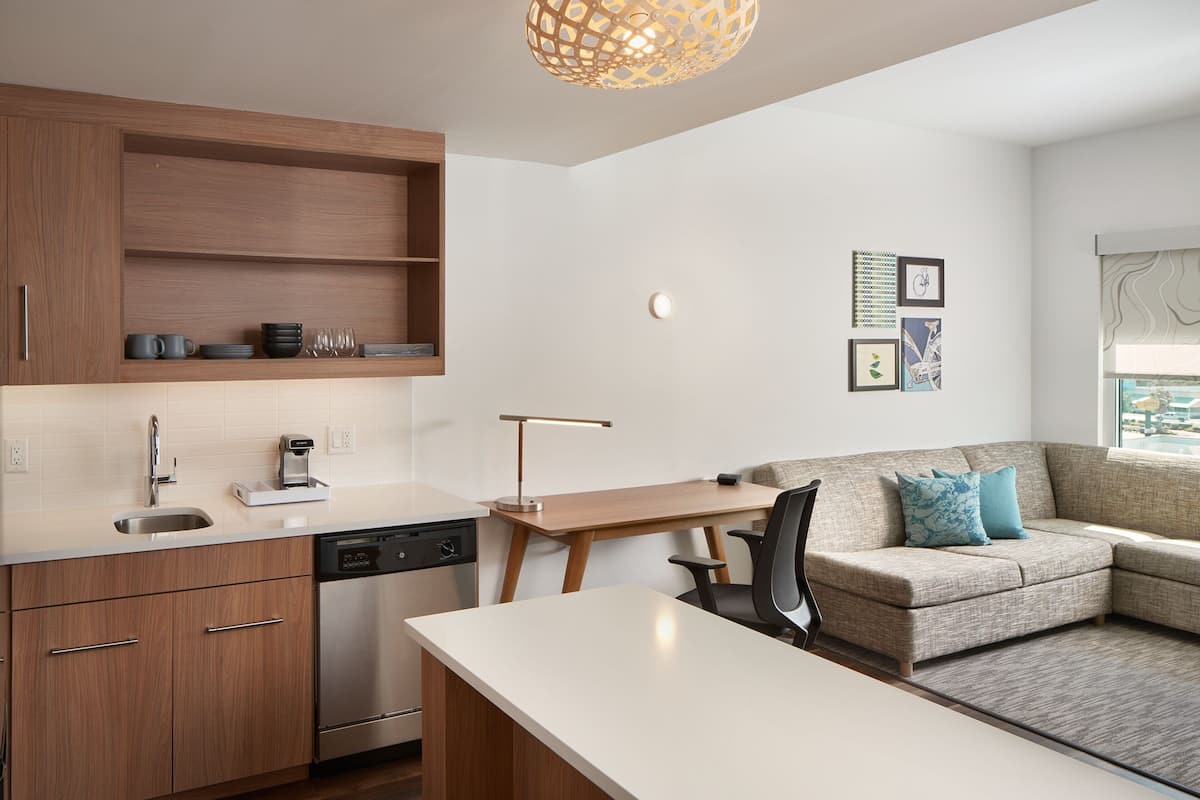 Een moderne keuken met houten kastjes, een vaatwasser en een eethoek met een tafel en stoelen.