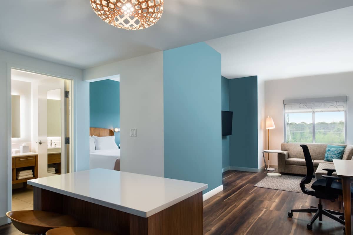 Een moderne hotelkamer met een groot bed, een bureau en een zithoek met uitzicht op de omgeving.