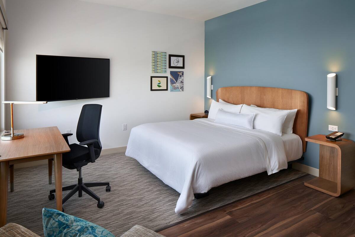 Hotelkamer met een bed, een bureau, een stoel, een televisie en wandlampen.