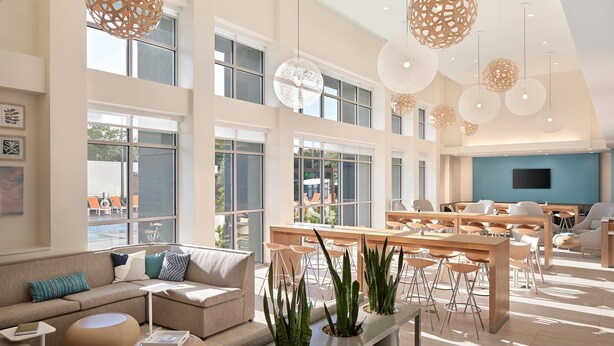 A spacious, well-lit hotel lobby with high ceilings, large windows, and modern furniture. - Element by Marriott Orlando at SeaWorld (Orlando)