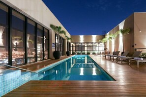 A modern indoor pool area with a long pool, lounge chairs, and potted plants. - Comfort Suites Sao Jose do Rio Preto (São José do Rio Preto)