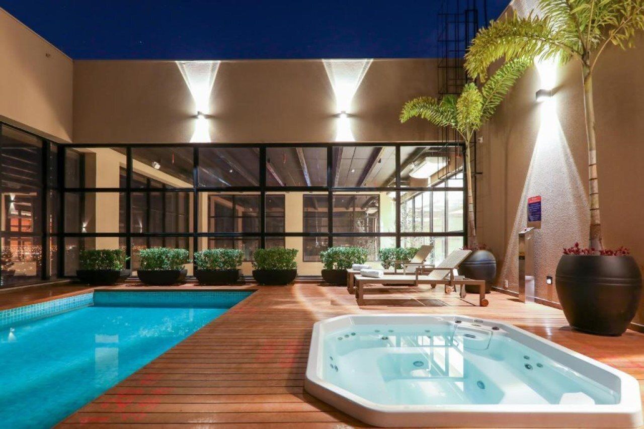 Een moderne binnenzwembadruimte met een jacuzzi, lounge stoelen en potplanten.